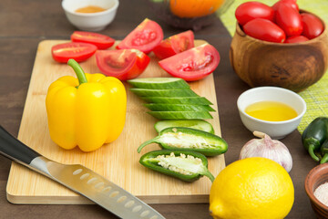 Different sliced vegetables for cooking salad on cutting board with knife on table on kitchen. Cooking healthy vegetarian vegan diet vegetable food concept