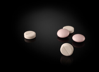 white and pink pills on a dark background