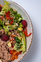 tuna salad with lettuce and eggs, lamb and fruit, fresh salad in a plate on a white background