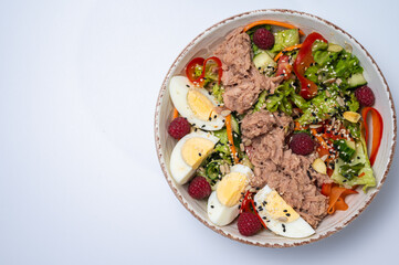 tuna salad with lettuce and eggs, lamb and fruit, fresh salad in a plate on a white background	
