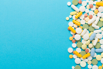 Different medical pills and capsules on color background, top view