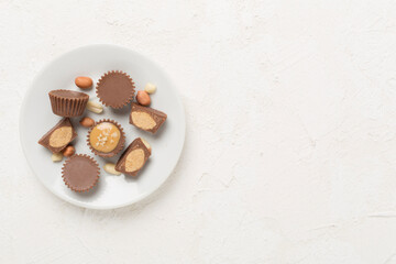 Delicious peanut butter cups with nuts on concrete background, top view