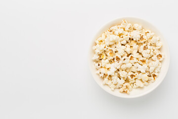 Tasty popcorn in bowl on color background, top view