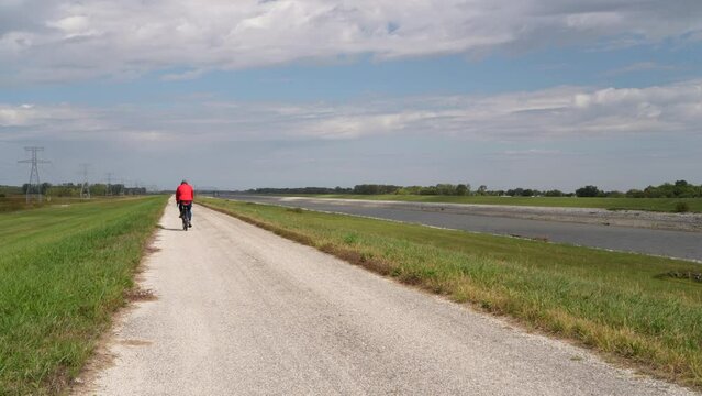 lonely cyclist is riding a gravel touring bike - biking on a levee trail along Chain of Rocks Canal near Granite City in Illinois
