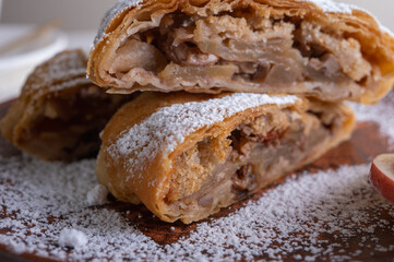 Paired pieces of delicious strudel stuffed with apples and cinnamon on a light plate on a light background. Place for writing. Close up view. Homemade Ukrainian pastries	

