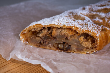 Paired pieces of delicious strudel stuffed with apples and cinnamon on a light plate on a light background. Place for writing. Close up view. Homemade Ukrainian pastries	
