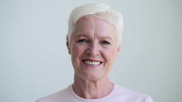 Serene presence of a Caucasian elderly woman emerges against a pristine white backdrop. Her face, marked by the wisdom of age, exudes a timeless grace and elegance.