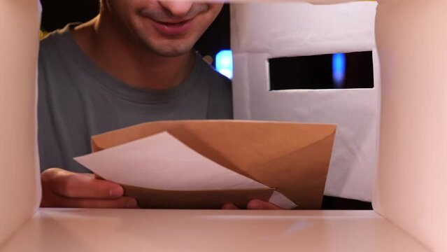 view from inside the mailbox, a man smiles and takes letters from the mailbox