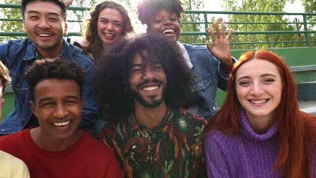 Happy playful multiethnic group of young friends standing together outdoors - multiracial millennial students meeting in the city, concepts of youth,