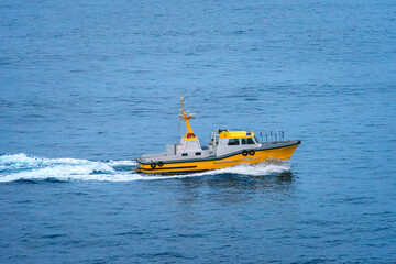 A yellow pilot boat speeding on the ocean water