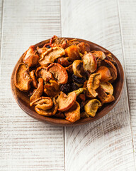 A mixture for dried fruit compote on a wooden plate on a white background.