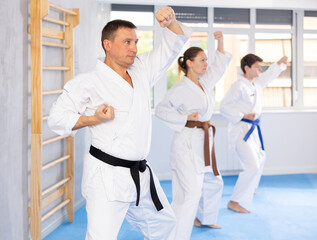 Kata karate teacher conducts classes and performs movements and fighting techniques together with students to prepare them for competitions.