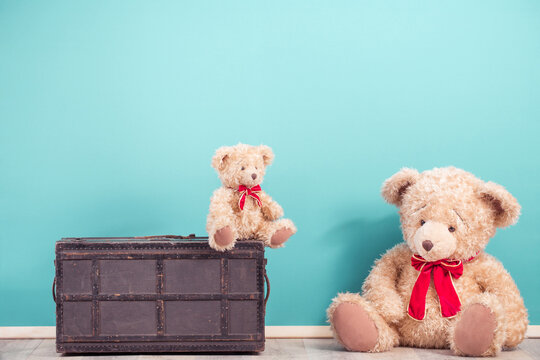 Teddy Bear toys and old vintage travel suitcase front mint blue wall background. Mother or father with baby concept. Retro style filtered photo
