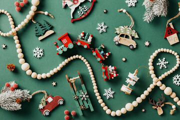 Vintage wooden Christmas toys and garland on green background. Flat lay, top view.