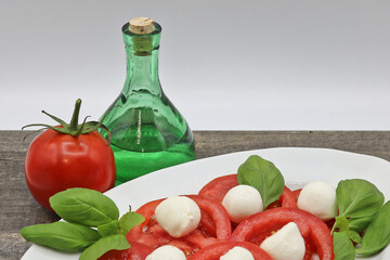 Tomato and Mozzarella Cheese Dish with Olive Oil and Basil served on the table