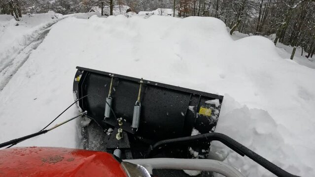 POV: Easy removal of heavy snowpack from the access road with a mini snowplow. A practical machinery to replace snow shovelling on the driveway. Winter chores in the countryside after snowfall