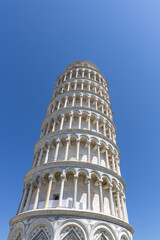 The leaning tower of Pisa, Italy in perspective shot from the ground. Summer day, clear blue sky...