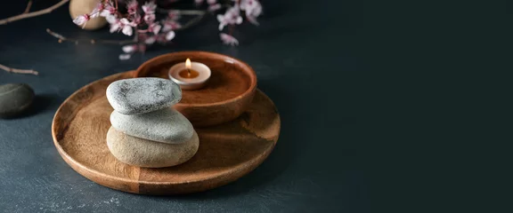 Fotobehang Badkamer Wooden tray with stack of spa stones and candle on dark background with space for text  © Pixel-Shot