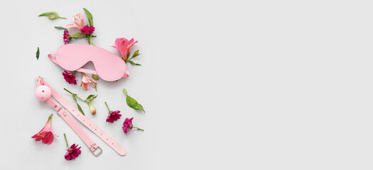 BDSM sex toys and flowers on light background with space for text