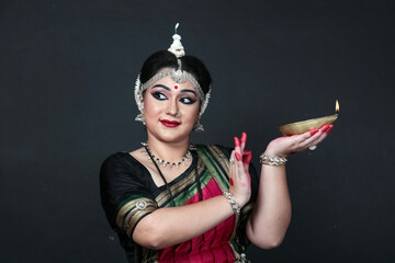 Indian female odishi dancer celebrating Diwali or deepavali, fesitval of lights at temple. Female hands holding oil lamp.