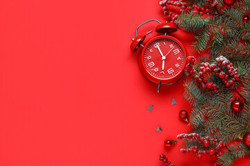 Composition with alarm clock, fir branches and Christmas decorations on red background