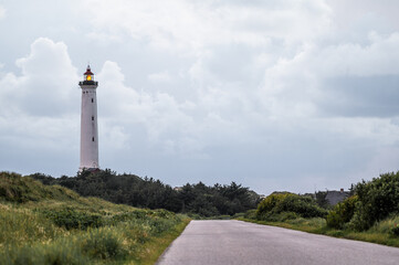 The majestic Hvide Sande Lighthouse stands tall on the Danish coast, a symbol of maritime heritage and safety. Its bold red and white stripes contrast beautifully against the coastal landscape. This i