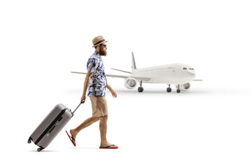 Full length profile shot of a bearded man with a suitcase walking in front of a plane