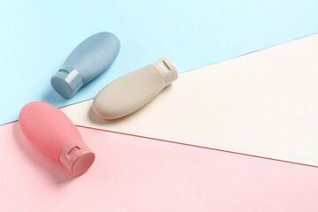 Bottles of travel cosmetic products on color background