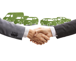 Men shaking hands in front of a green electic vehicles