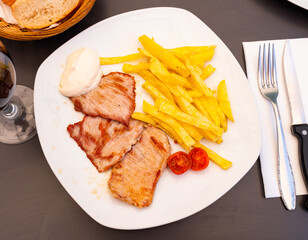 Delicious fried beef filet with freshly ground pepper served french fries with white sauce.