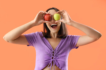 Beautiful young woman with fresh apples on orange background