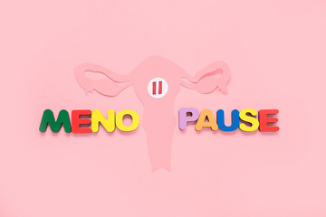 Word MENOPAUSE with paper uterus on pink background