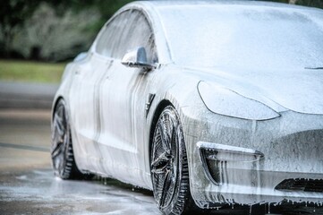 Manual car wash. Washing luxury vehicle with white foamy detergent. Automobile cleaning self service