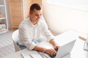 Handsome young businessman working with laptop at workplace in office