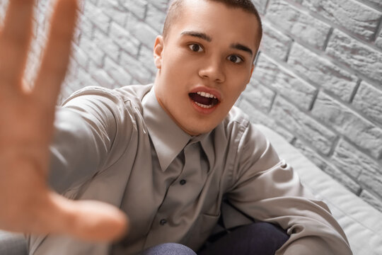 Afraid young man in living room near brick wall