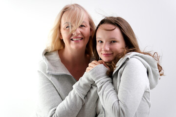 beautiful people two women mother and daughter look into frame and then at each other smile tenderness identical clothes models on white background in studio laugh smile. touch nose to your cheek