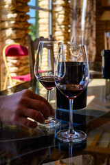 Tasting of red dry wine in Chateauneuf-du-Pape wine making village in France with green vineyards on large pebbles galets and sandstone clay soil