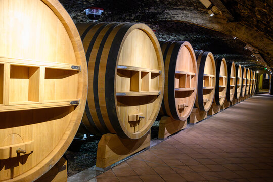 Underground wine cellars with barrels for aging of red dry wine in Chateauneuf-du-Pape wine making village in France with green vineyards on large pebbles galets and sandstone clay soil