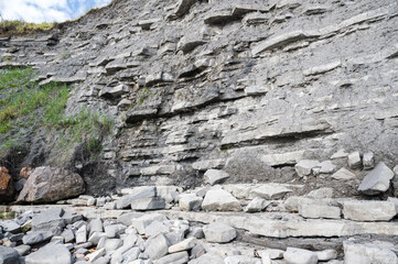 Cliffs in East Cliff beach in Lyme Regis, Dorset, South West England. Close up of stacked under time stones. Selective focus
