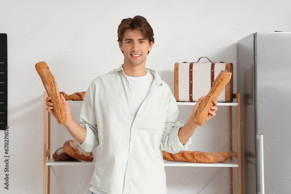 Poster Handsome young man with loaves of fresh bread in bakery