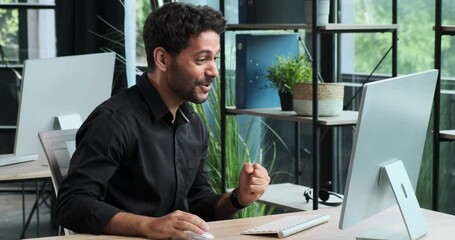 Exhausted Middle Eastern office worker yawns while seated at the desk. His weariness underscores the demands of a long day's work, emphasizing the importance of maintaining energy and focus.