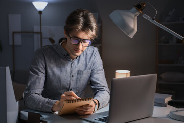 Young businessman writing in notebook at office