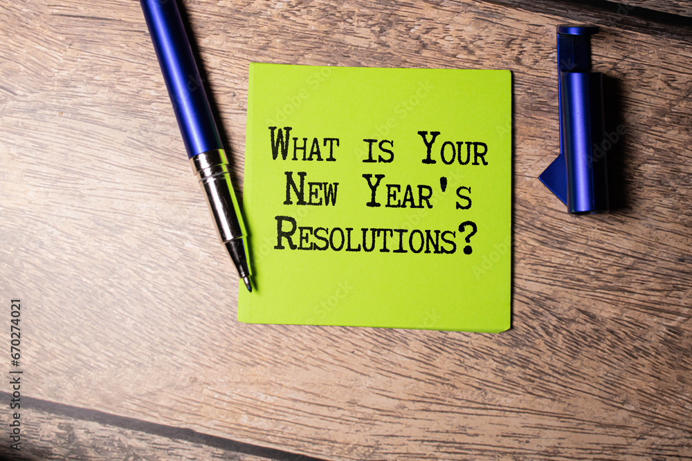 Poster top view of office desk and notepad with text - what is your new year's resolutions.