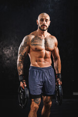 Fototapeta na wymiar Bodybuilder Standing In The Gym With Weight Plate