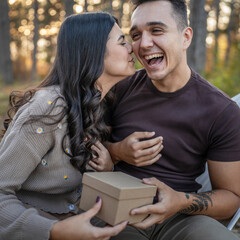 Young couple man and woman give present gift box while sit in nature