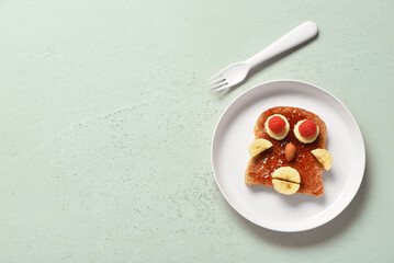 Plate with funny children's breakfast in shape of human face on grey table