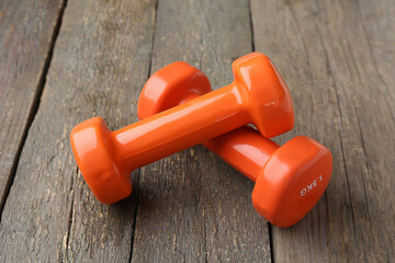 Orange dumbbells on wooden background