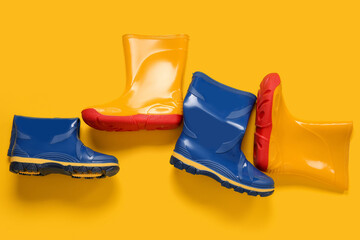 Different stylish gumboots on yellow background