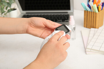 Young woman cleaning smart watch on white table