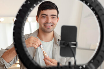 Male beauty blogger with highlighter recording video in makeup room, closeup